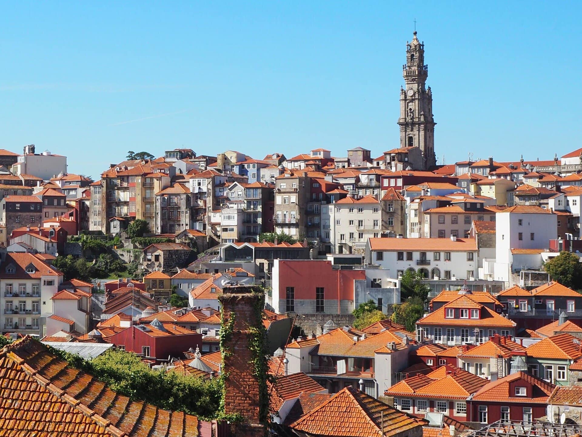Cityscape with red-tiled rooftops and Porto’s tall historic clock tower under a clear blue sky, perfect for any travel guide or list of things to do in the city.
