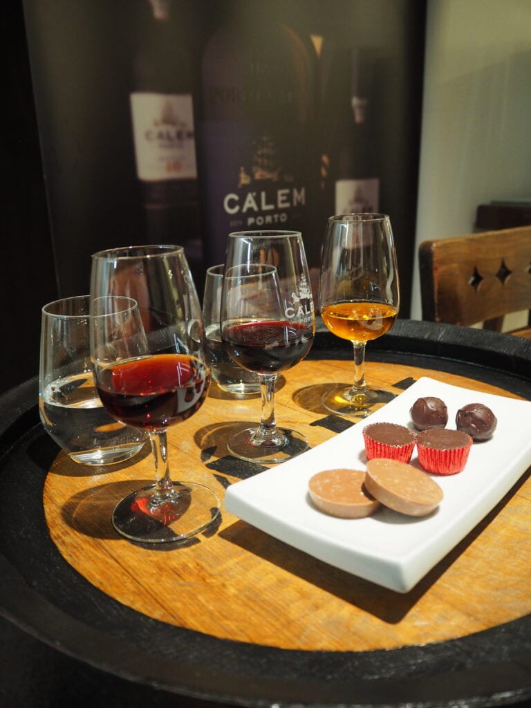 Four glasses of port wine and water with chocolates on a tray, set for a tasting experience—perfect inspiration if you're wondering where to eat in Oporto.