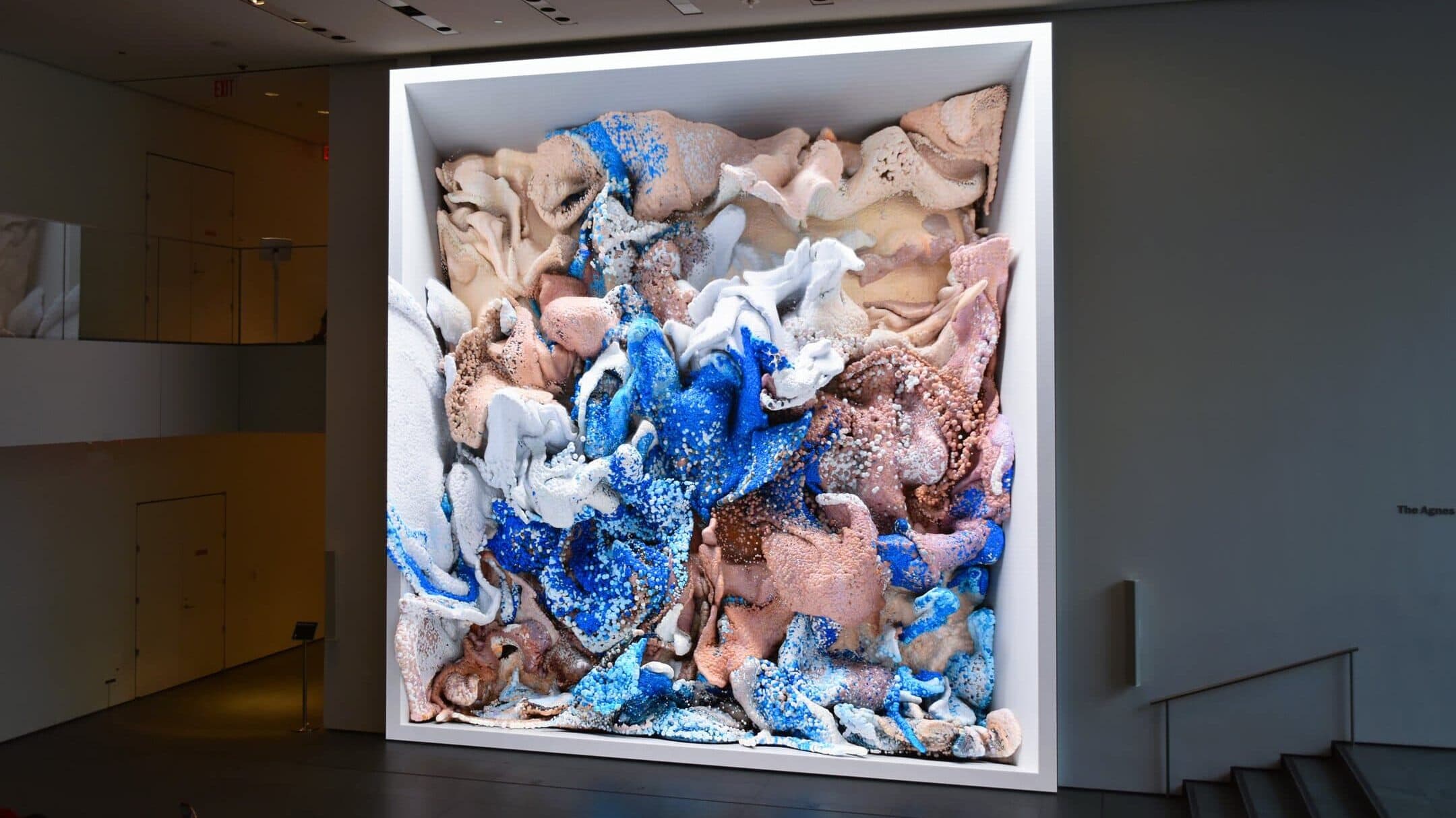 Large abstract artwork with swirling 3D shapes in beige, white, and blue, displayed on a museum wall—an inspiring piece you might find if you visit MoMA in New York (Museum of Modern Art).