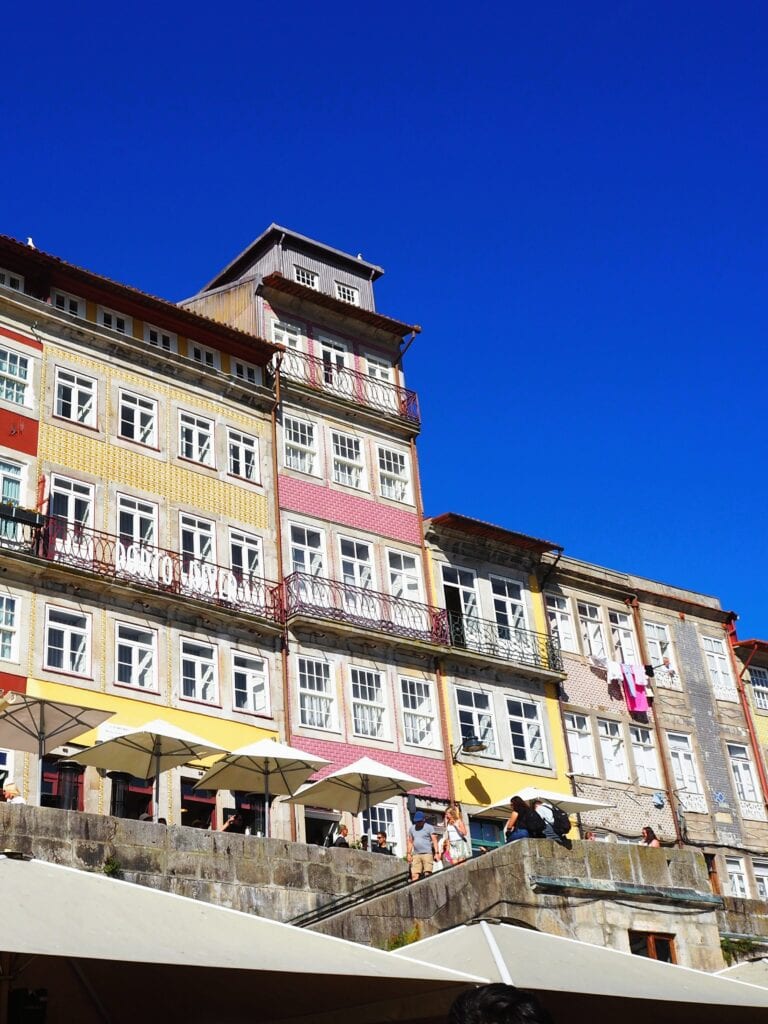 Colourful buildings with balconies and umbrellas beneath, set against a clear blue sky—perfectly capturing the vibrant charm you’d experience during one day in Porto.