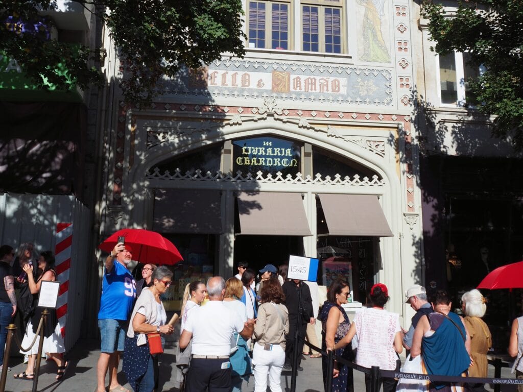 People wait in queue outside Livraria Lello, a historic bookshop with ornate architecture and a decorative façade—a must-see destination if you have just one day in Porto.
