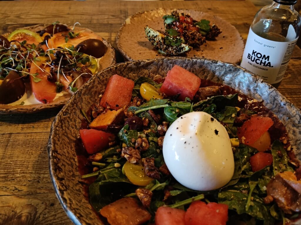 Burrata salad, heirloom tomato dish, and kombucha on a rustic wooden table—the perfect lunch to savour during one day in Porto.